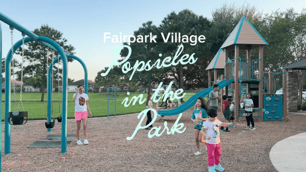 Children play on swings and a playground slide in a community park, with overlaid text reading “Fairpark Village Popsicles in the Park"